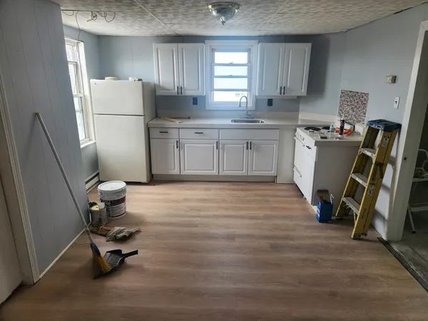 a kitchen with a refrigerator a stove and wooden floor