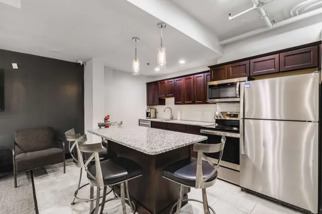 a kitchen with stainless steel appliances a refrigerator a stove a dining table and chairs