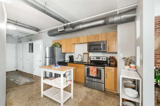 a kitchen with stainless steel appliances granite countertop a stove top oven a sink a dining table and chairs