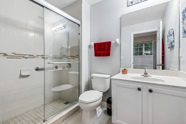 a bathroom with a toilet sink vanity granite and shower