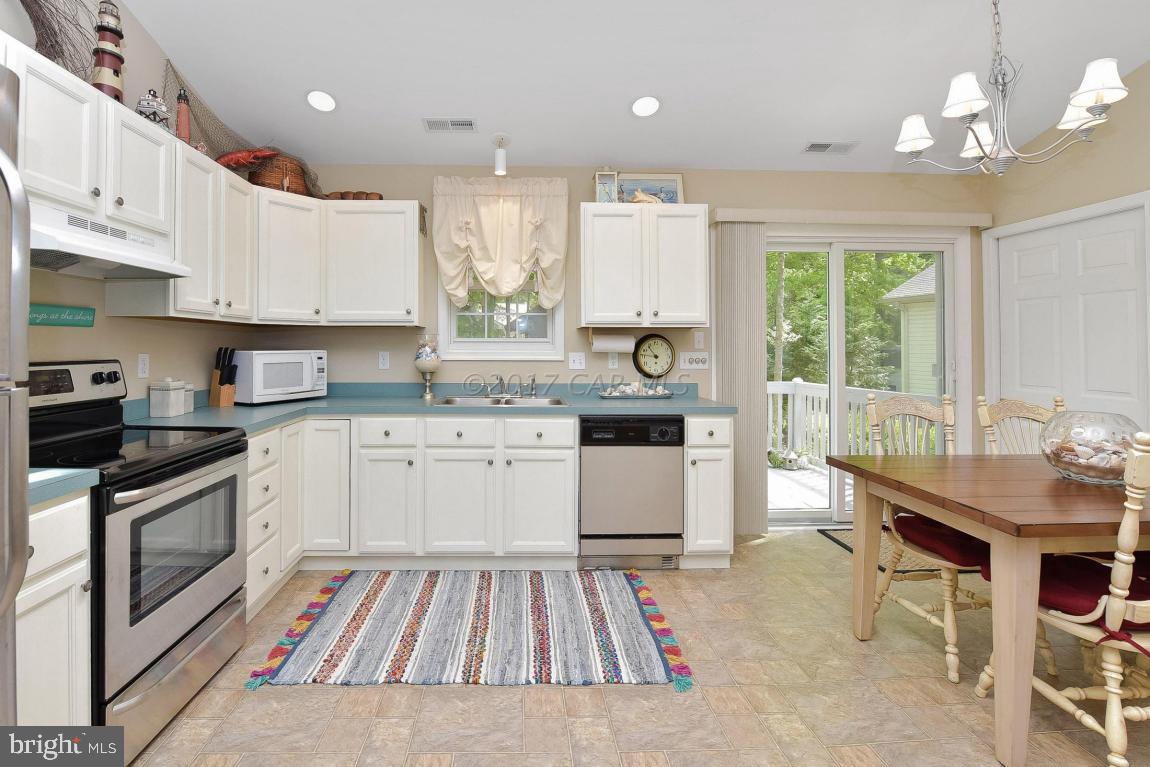29 Watertown Road Ocean Pines, MD 21811 - Photo 7 of 49 a kitchen with a stove a sink dishwasher a microwave oven and a dining table with wooden floor