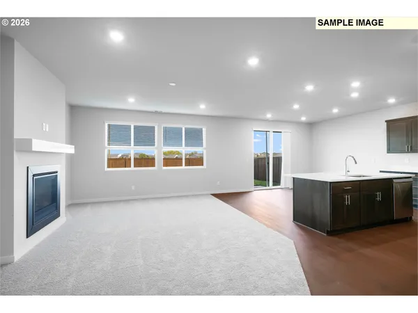 a view of an empty room with a kitchen and fireplace