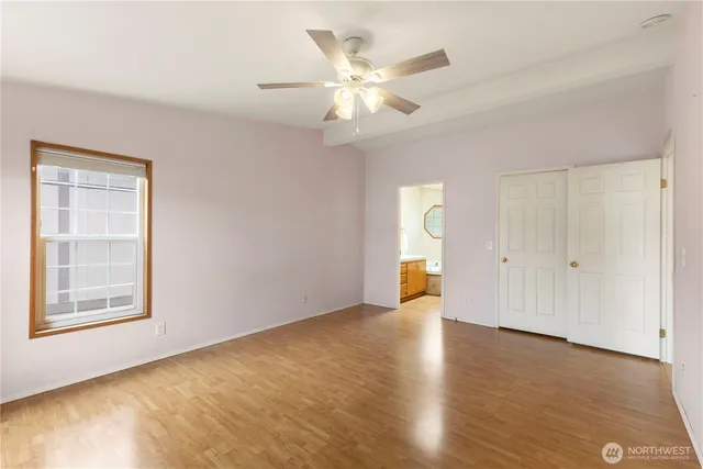 a view of an empty room with a window and wooden floor