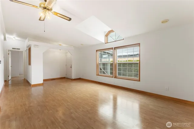 a view of an empty room with a window and wooden floor