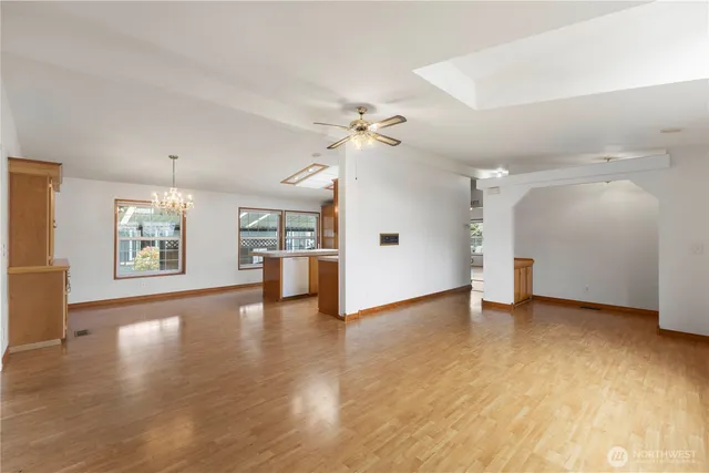 a large kitchen with stainless steel appliances kitchen island granite countertop a table chairs and a wooden floor