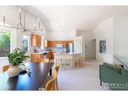 a living room with furniture potted plant kitchen view and a large window