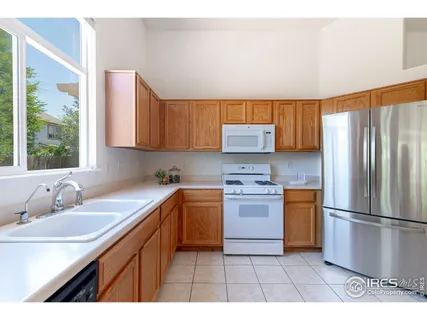 a kitchen with stainless steel appliances granite countertop a sink a stove a refrigerator with grey cabinets