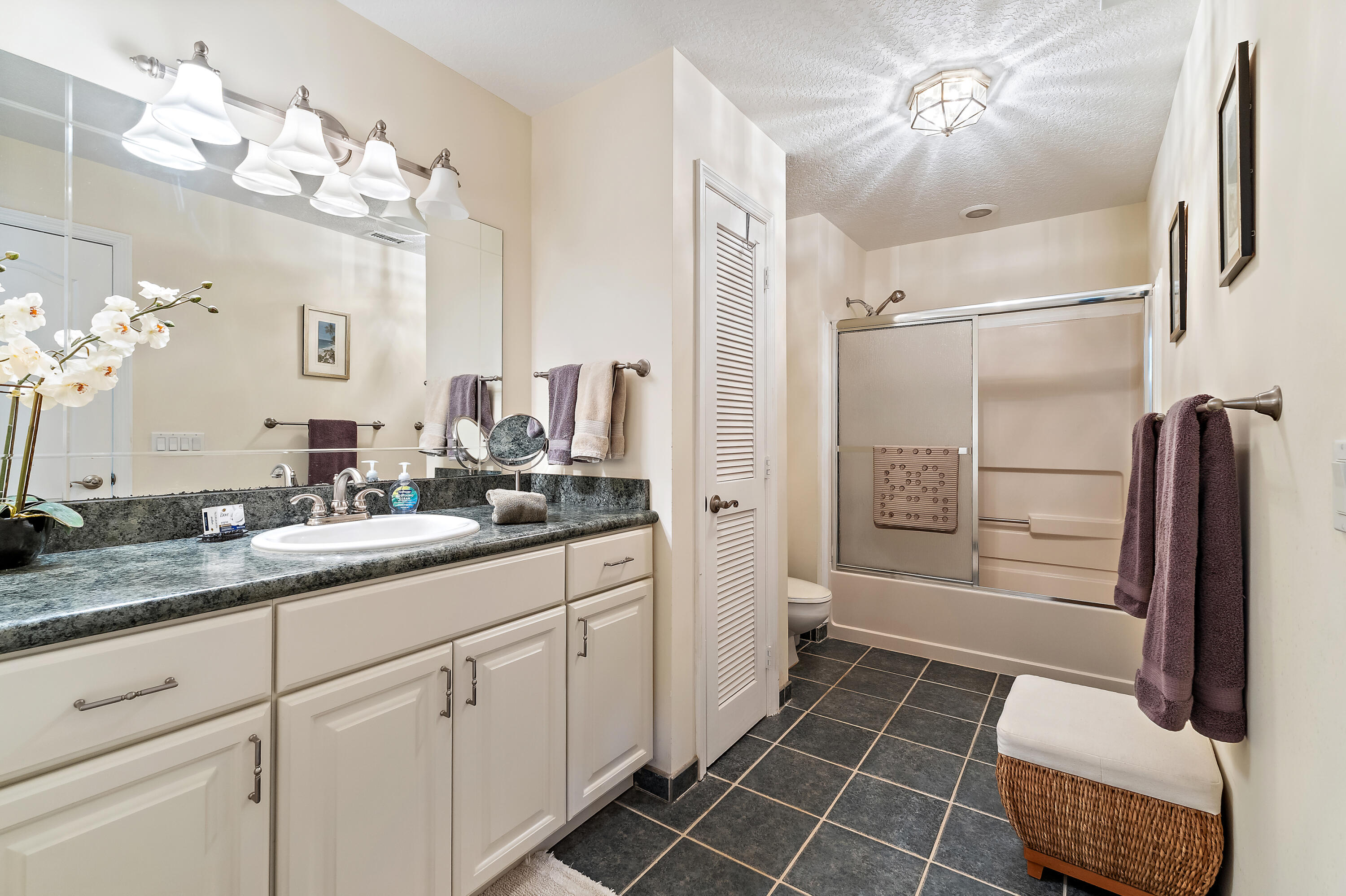 1420 Ocean Way, Unit 28D Jupiter, FL 33477 - Photo 27 of 33 a bathroom with a double vanity sink a toilet a mirror and shower