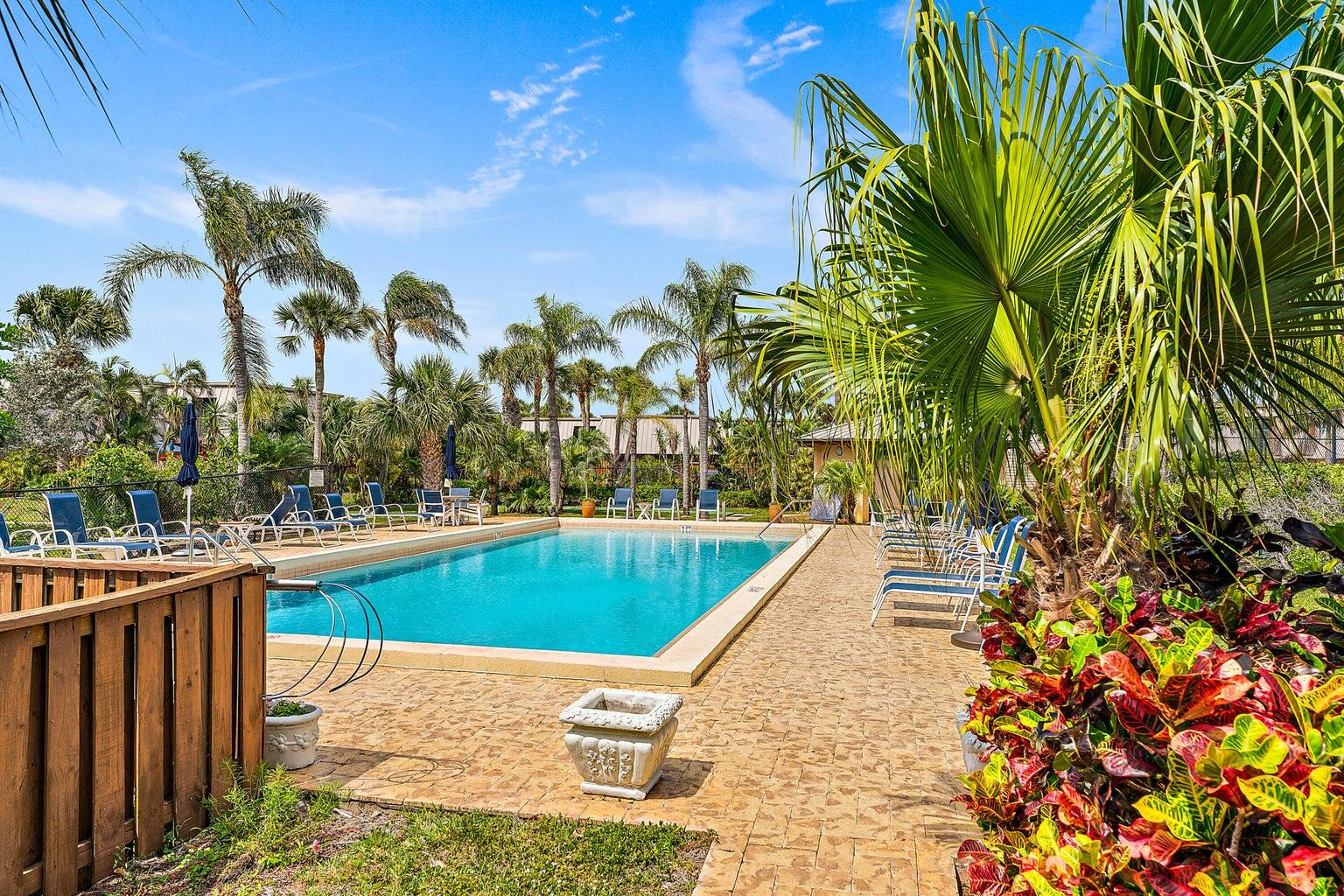 1420 Ocean Way, Unit 28D Jupiter, FL 33477 - Photo 28 of 33 a view of a swimming pool with a lawn chairs under an umbrella