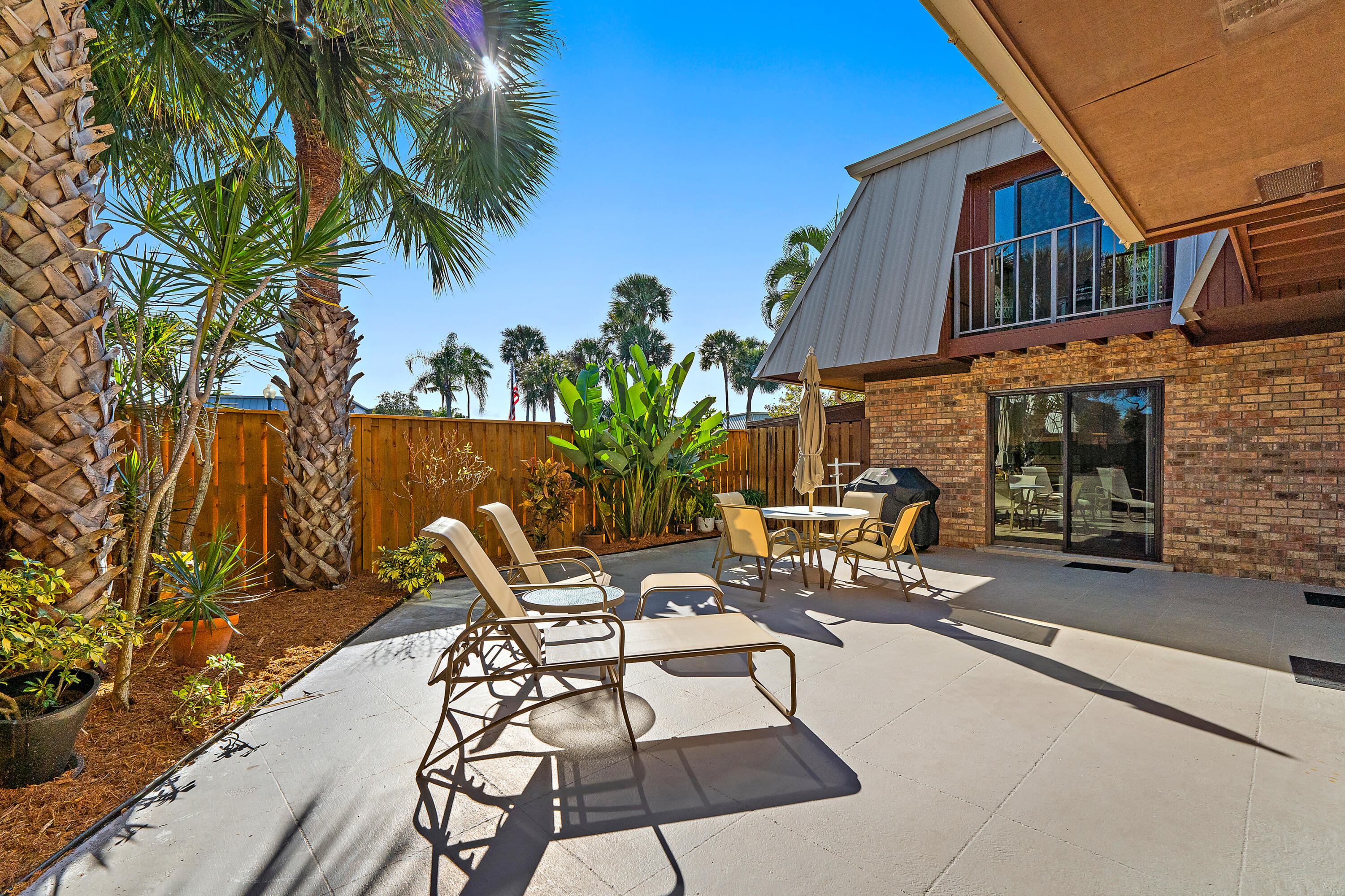 1420 Ocean Way, Unit 28D Jupiter, FL 33477 - Photo 4 of 33 a view of a patio with table and chairs and potted plants with wooden floor and fence