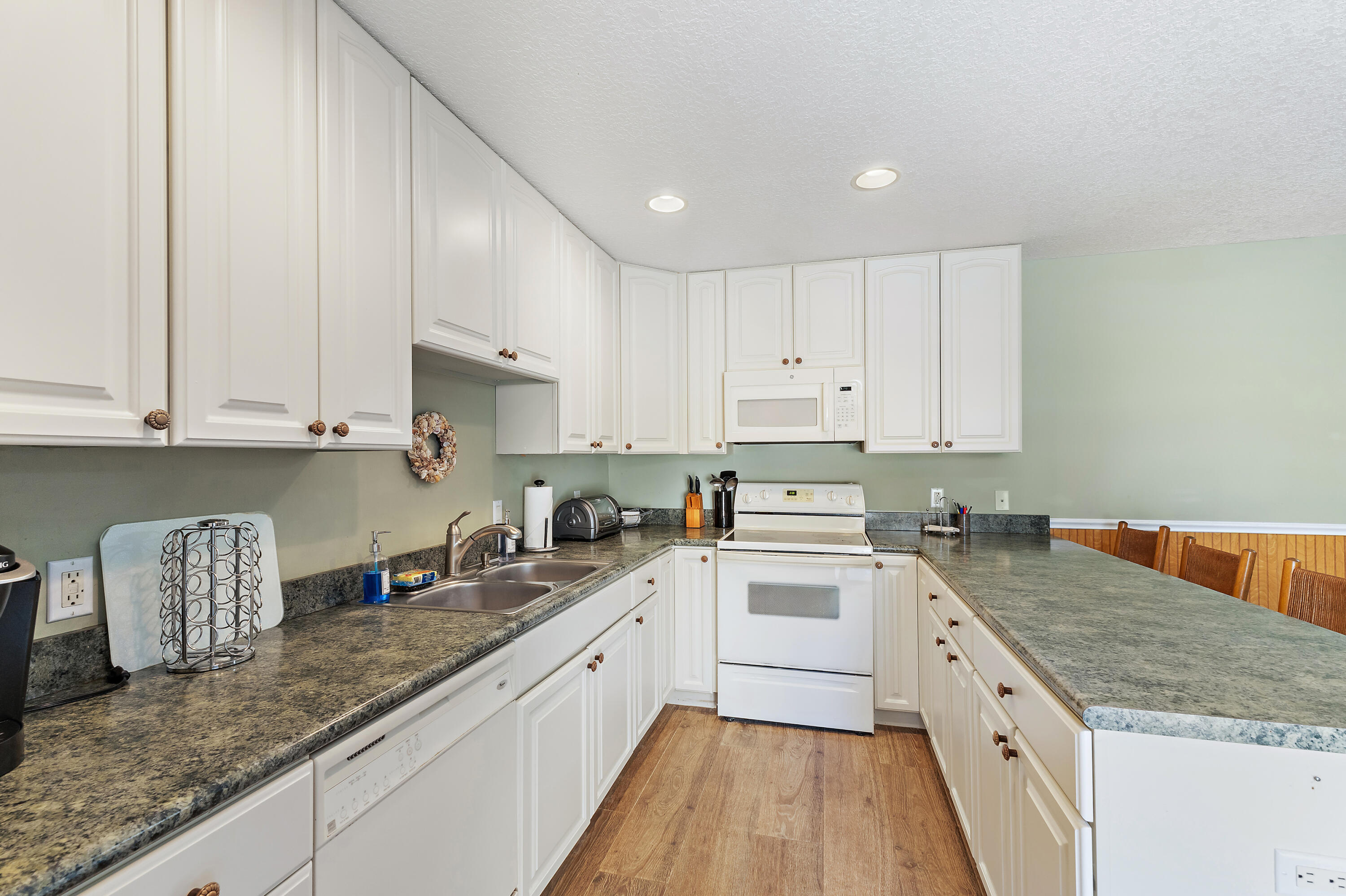 1420 Ocean Way, Unit 28D Jupiter, FL 33477 - Photo 6 of 33 a kitchen with granite countertop white cabinets and white appliances