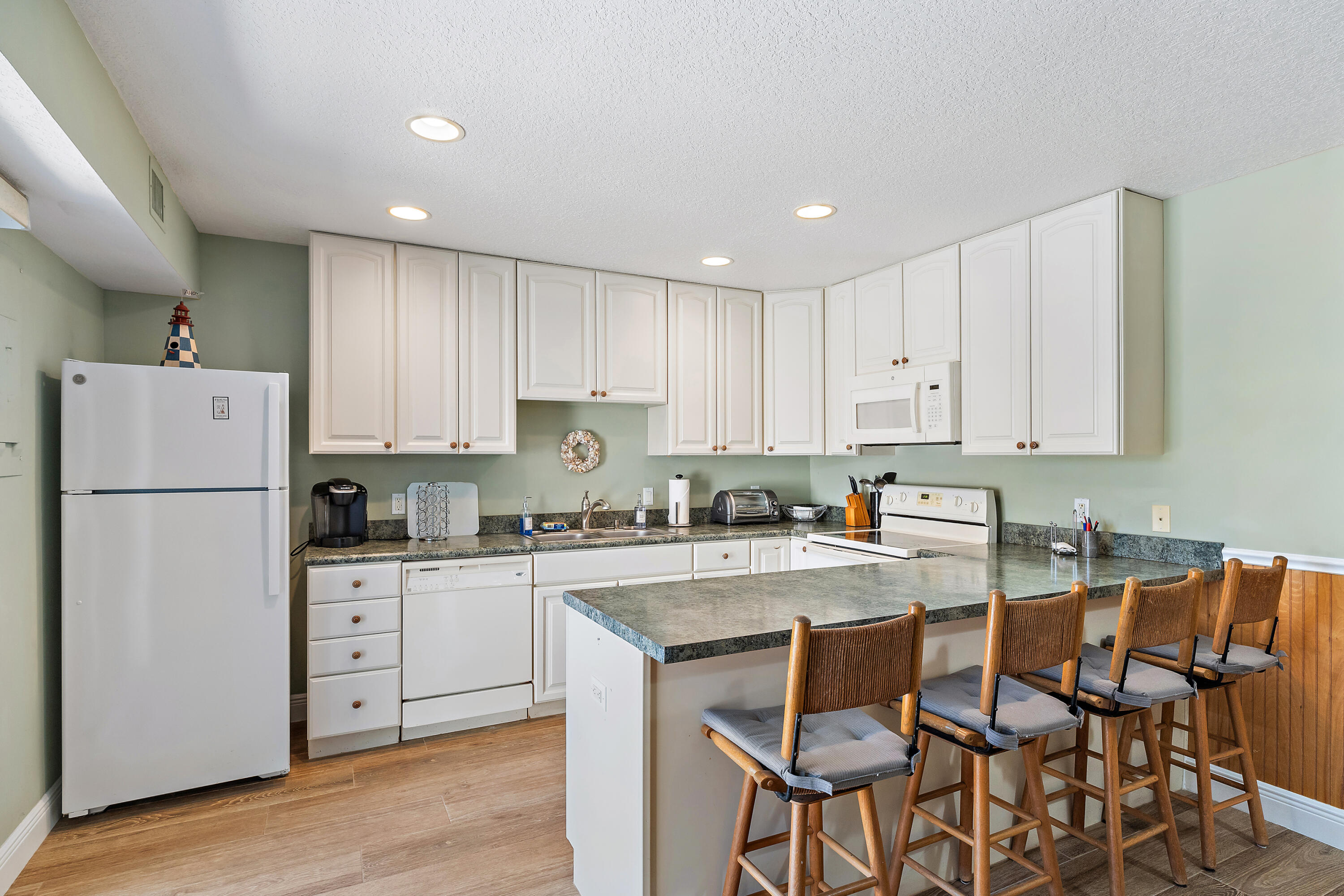 1420 Ocean Way, Unit 28D Jupiter, FL 33477 - Photo 7 of 33 a kitchen with stainless steel appliances granite countertop a stove a sink a refrigerator and white cabinets with wooden floor