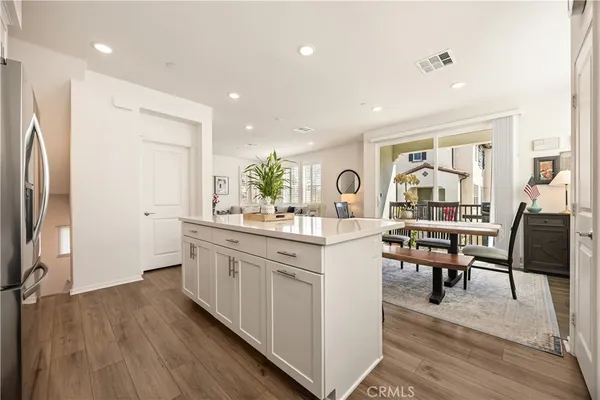 a kitchen with stainless steel appliances a refrigerator a stove a sink and white cabinets with wooden floor