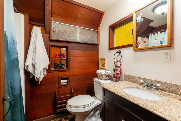 a bathroom with a granite countertop toilet sink and mirror