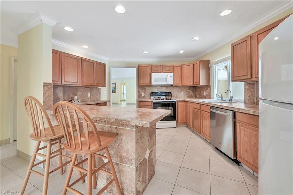 639 Pompano Drive Naples, FL 34110 - Photo 8 of 39 a kitchen with stainless steel appliances kitchen island granite countertop a stove a sink a dining table and chairs