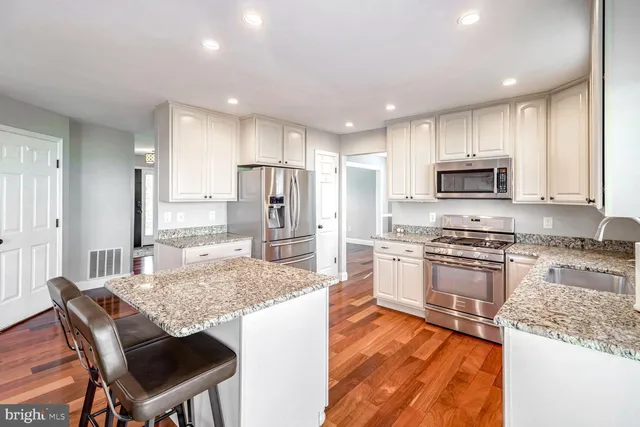 a kitchen with stainless steel appliances granite countertop a stove top oven a refrigerator a sink and a refrigerator