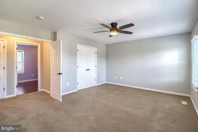 an empty room with closet and a ceiling fan