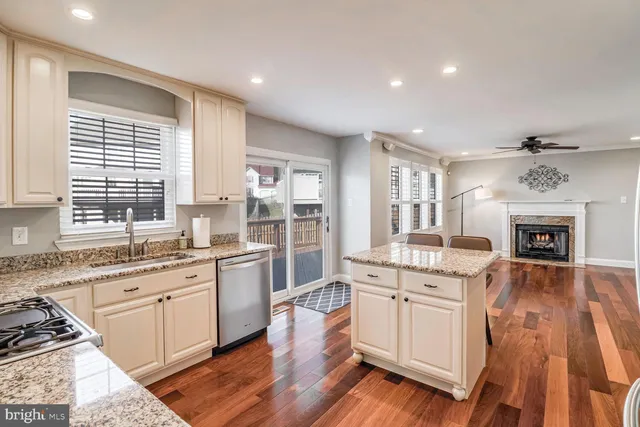 a large kitchen with granite countertop a stove top oven a sink dishwasher and white cabinets with wooden floor