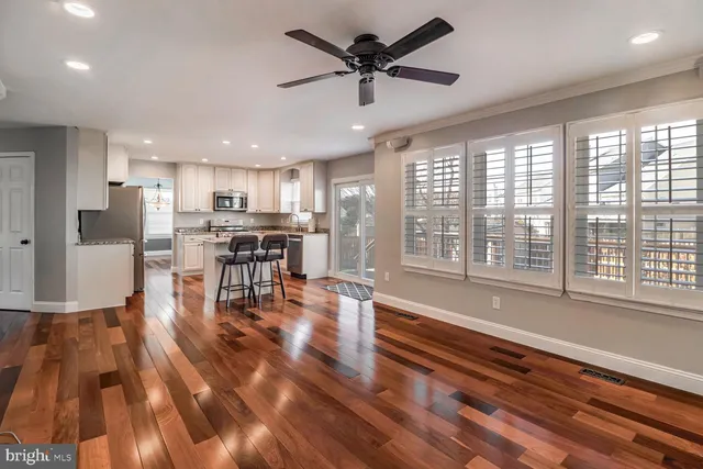 a kitchen with stainless steel appliances granite countertop a stove top oven a refrigerator a dining table and chairs with wooden floor