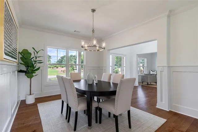 a hallway with wooden floor table and chairs