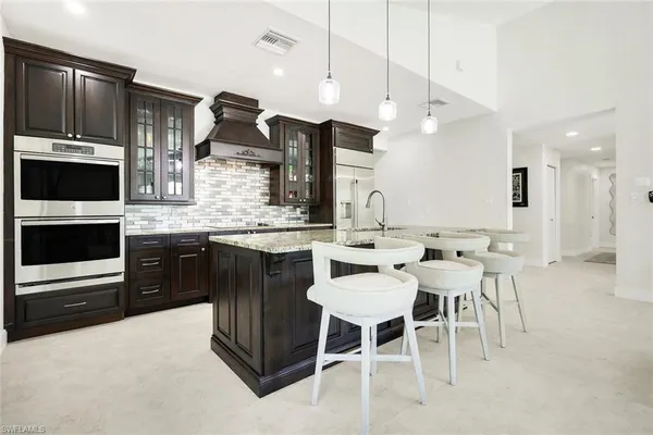 a kitchen with stainless steel appliances kitchen island granite countertop a table chairs and a refrigerator