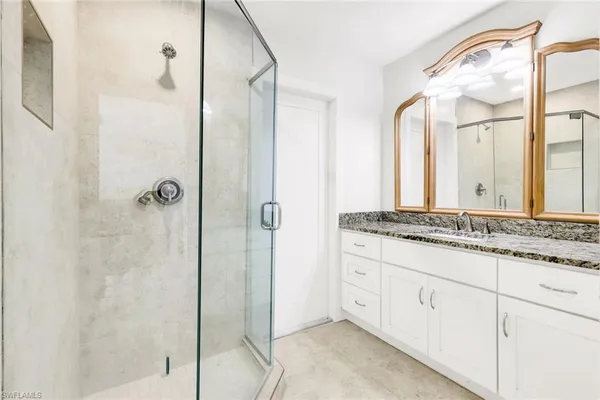 a bathroom with a granite countertop sink a mirror and a shower