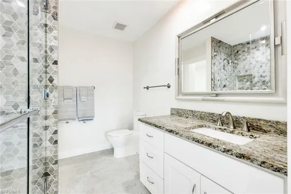 a bathroom with a granite countertop sink a toilet and shower