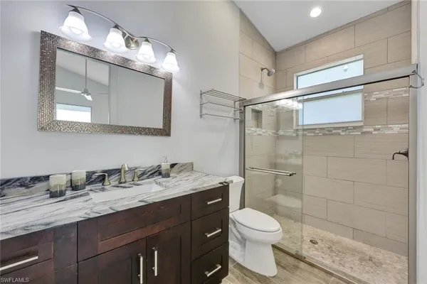 a bathroom with a granite countertop sink toilet and shower