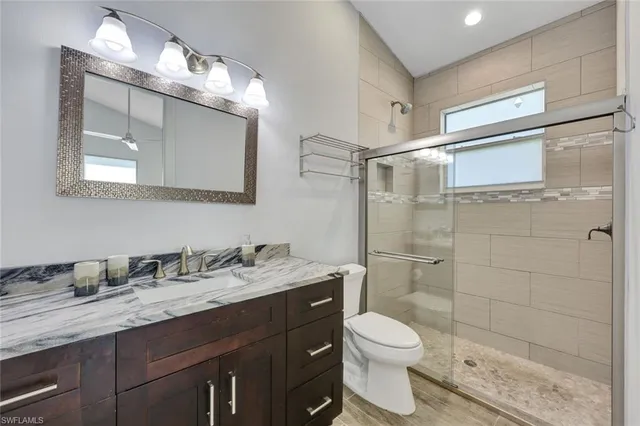 a bathroom with a granite countertop sink toilet and shower