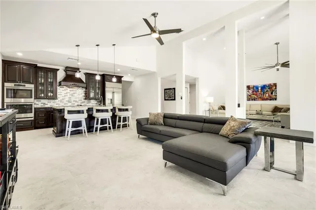 a living room with furniture kitchen view and a large window