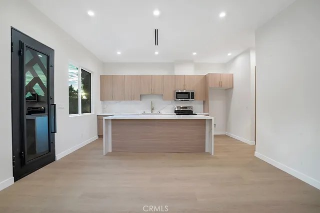 a view of kitchen with kitchen island granite countertop stainless steel appliances refrigerator and microwave