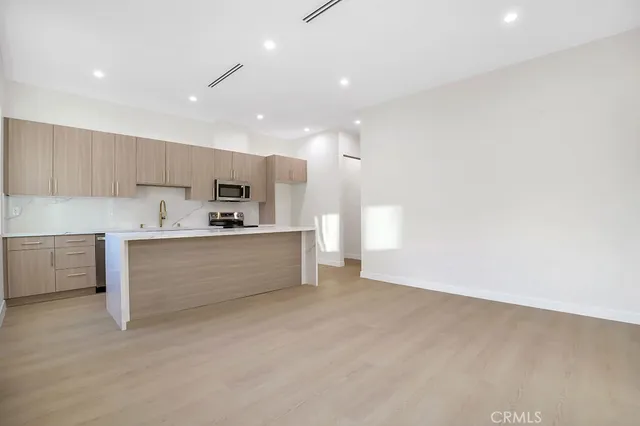 a large white kitchen with kitchen island a sink stainless steel appliances and cabinets