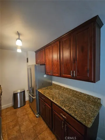 a kitchen with stainless steel appliances granite countertop wooden cabinets a refrigerator and a sink