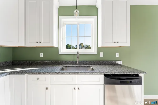 a kitchen with granite countertop a sink and white cabinets