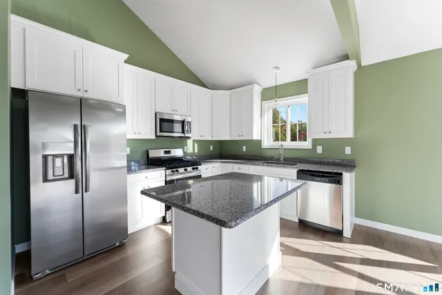 a kitchen with stainless steel appliances granite countertop a sink refrigerator and microwave