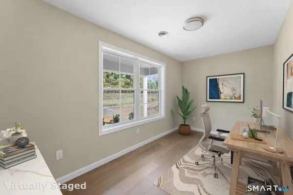 a view of an empty room with wooden floor and a window