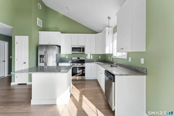 a kitchen with stainless steel appliances granite countertop a sink refrigerator and microwave