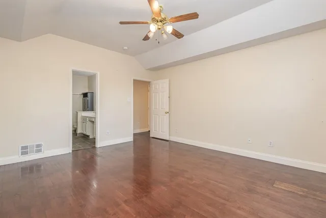an empty room with wooden floor and a ceiling fan