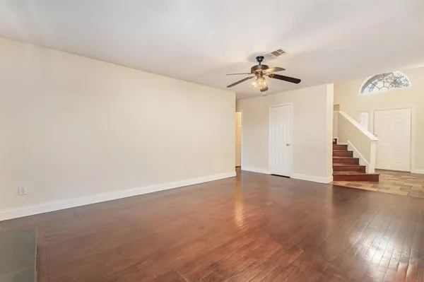 an empty room with wooden floor and ceiling fan
