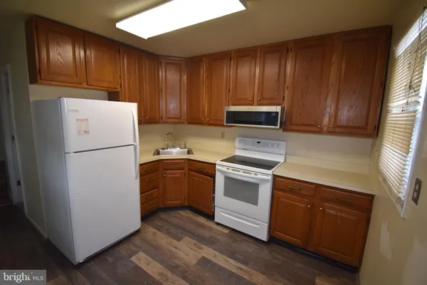 a kitchen with granite countertop wooden cabinets and white appliances