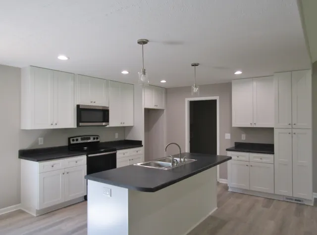 a kitchen with stainless steel appliances granite countertop a sink a stove and microwave