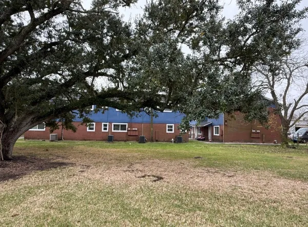 a view of a house with a yard and large trees