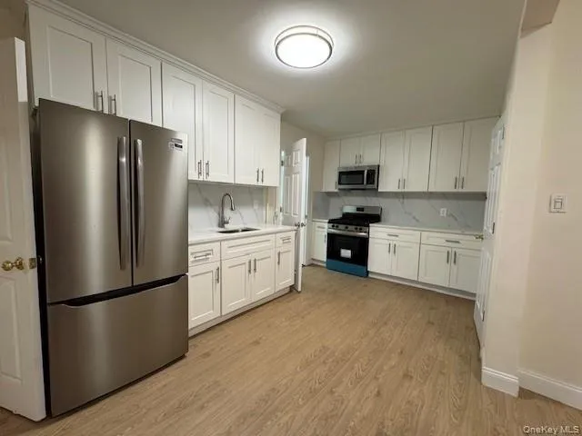 a kitchen with a refrigerator a microwave a sink and cabinets