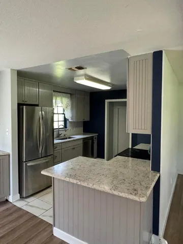 a kitchen with stainless steel appliances granite countertop a refrigerator a sink a stove and island