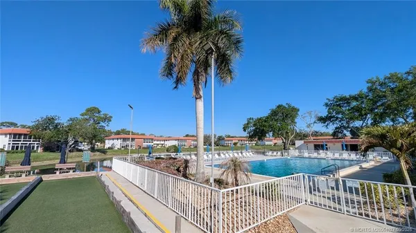 a view of a white house with a yard and table and chairs under an umbrella