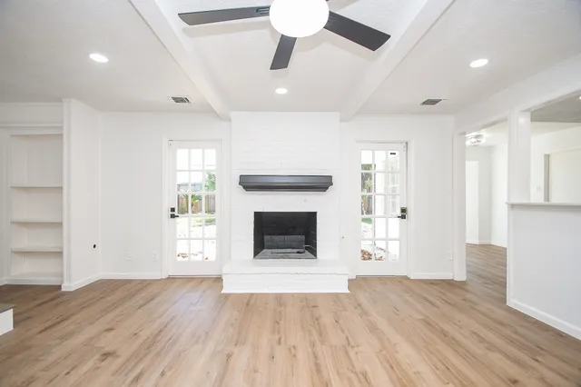 wooden floor fireplace and windows in an empty room