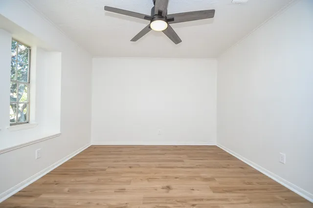 an empty room with wooden floor cabinet and windows