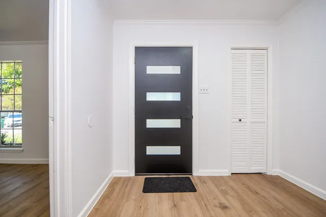 an empty room with wooden floor windows and closet