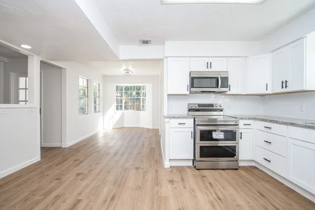 a kitchen with granite countertop a stove a sink and a microwave