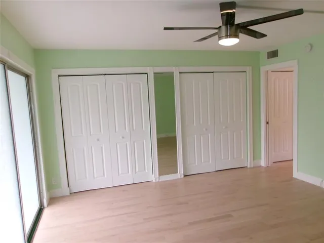 an empty room with ceiling fan and window
